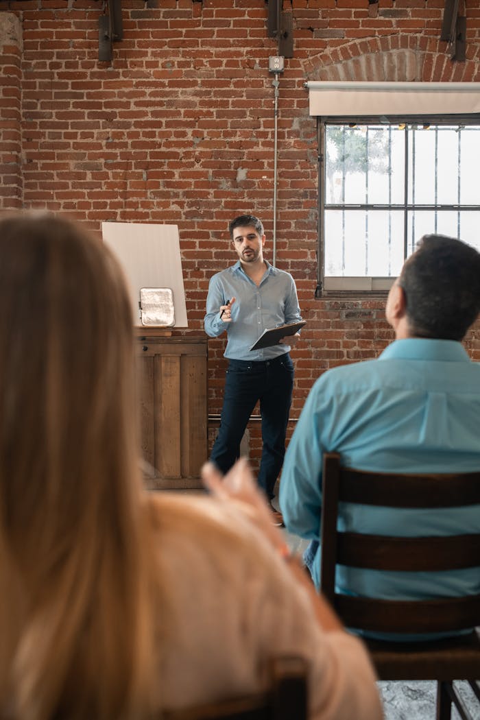 Man teaching an adult education class with brick wall backdrop.