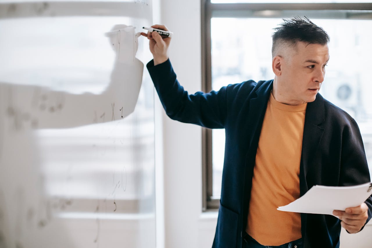 Male teacher explaining concepts on a whiteboard during a lesson indoors.